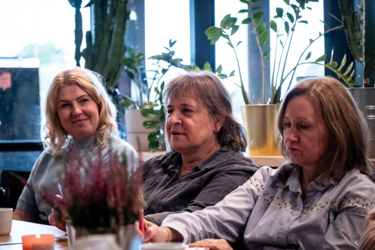 Trzy kobiety siedzące razem przy stole podczas spotkania.